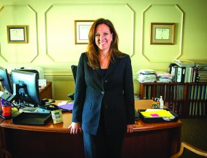 Dr. Carol Birnbohm stands in front of her desk in her office.