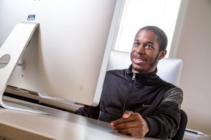 A student sits at a desktop computer.