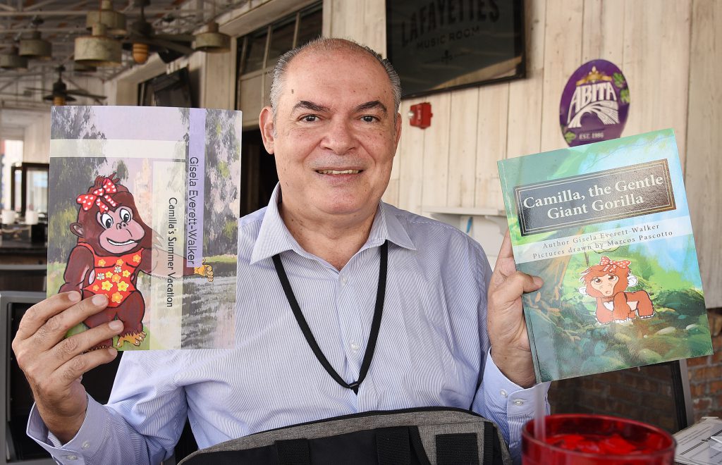 Marcos Pascotto, a student from Brazil, holds up children’s books he illustrated called about Camilla the gentle giant gorilla.
