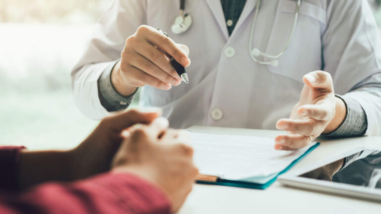 A person in a lab coat reviews a chart with a patient