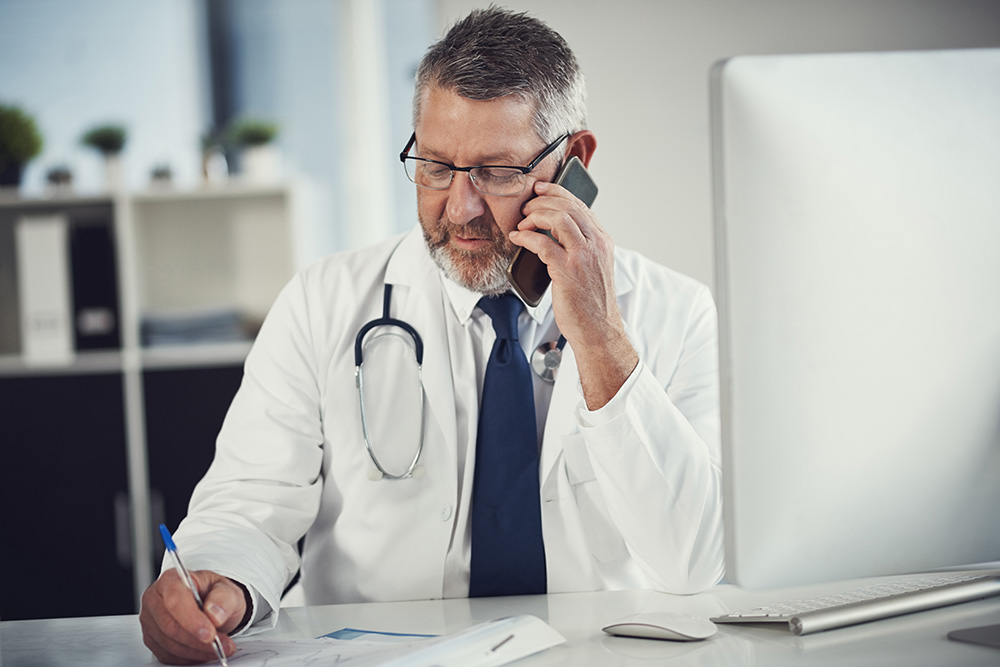 Doctor in lab coat speaks on cell phone