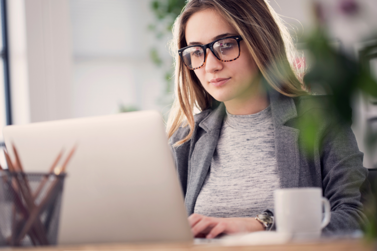 Woman wearing glasses types on her laptop