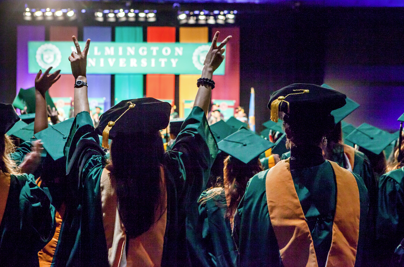 Woman holds up two hands at commencement in celebration