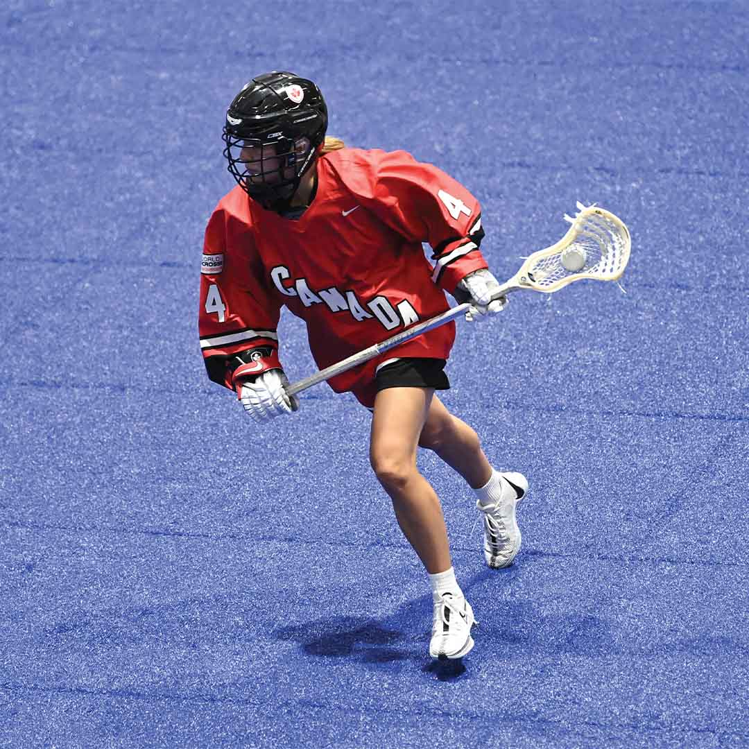 Ella Royer competing in a lacrosse match waring a red Canadian jersey.
