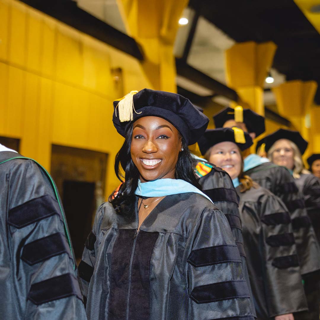 A smiling Wilmington University Ed.D. graduate walking into their graduation ceremony.