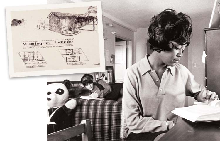 Two students in a dorm room next to architectural drawings of a dorm.