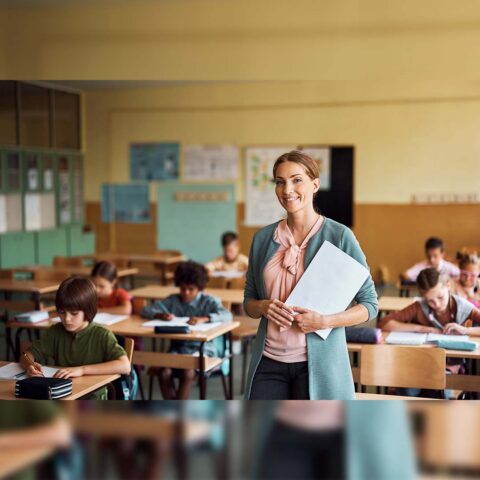 A teacher standing in their classroom with students working at their desks.
