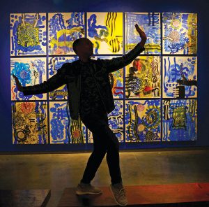 Davies strikes a pose in front of "Beijing Booster Paintings" by Peter Wayne Lewis at the Delaware Contemporary, at the Riverfront.