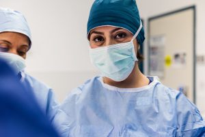 Female health professional wears protective equipment while looking at camera