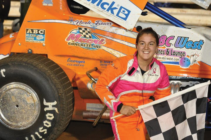 Nicole holds a checkered flag next to her sprint car