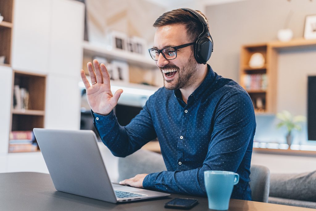 Man wears headphones while waving through webcam computer