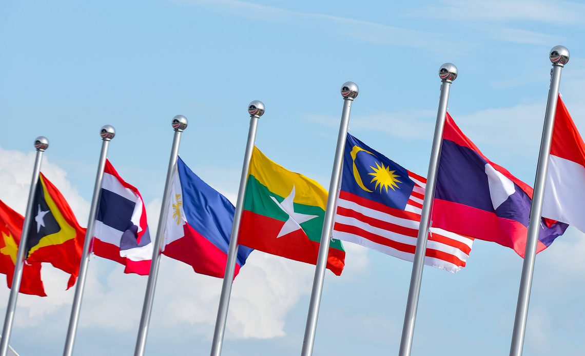 Flags of different nations fly against a blue sky