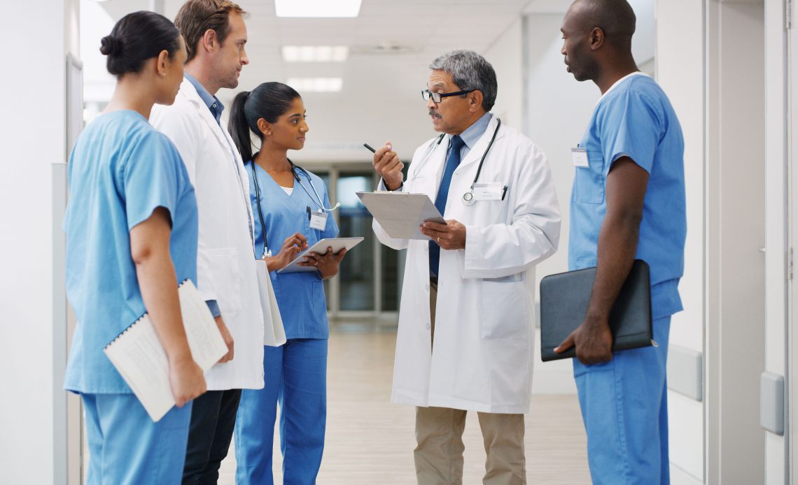 Health professionals stand in a hallway in discussion