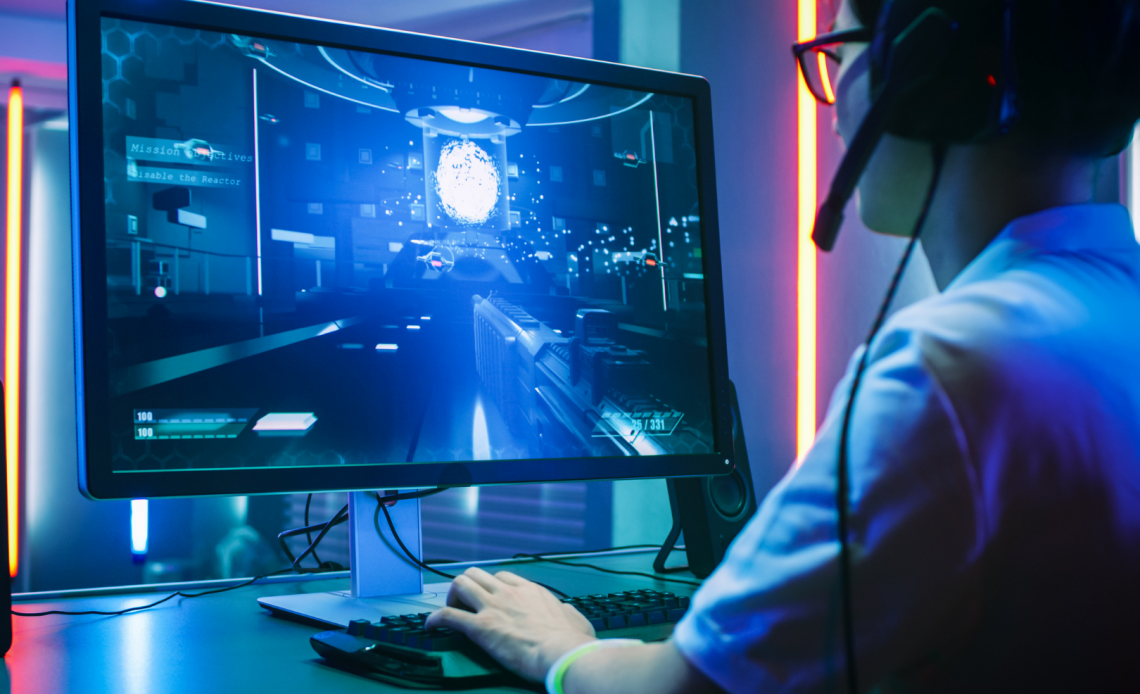 Man with headset plays computer game around neon red and blue lights
