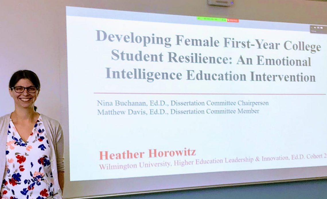 Dr Horowitz stands in front of her doctoral presentation slides