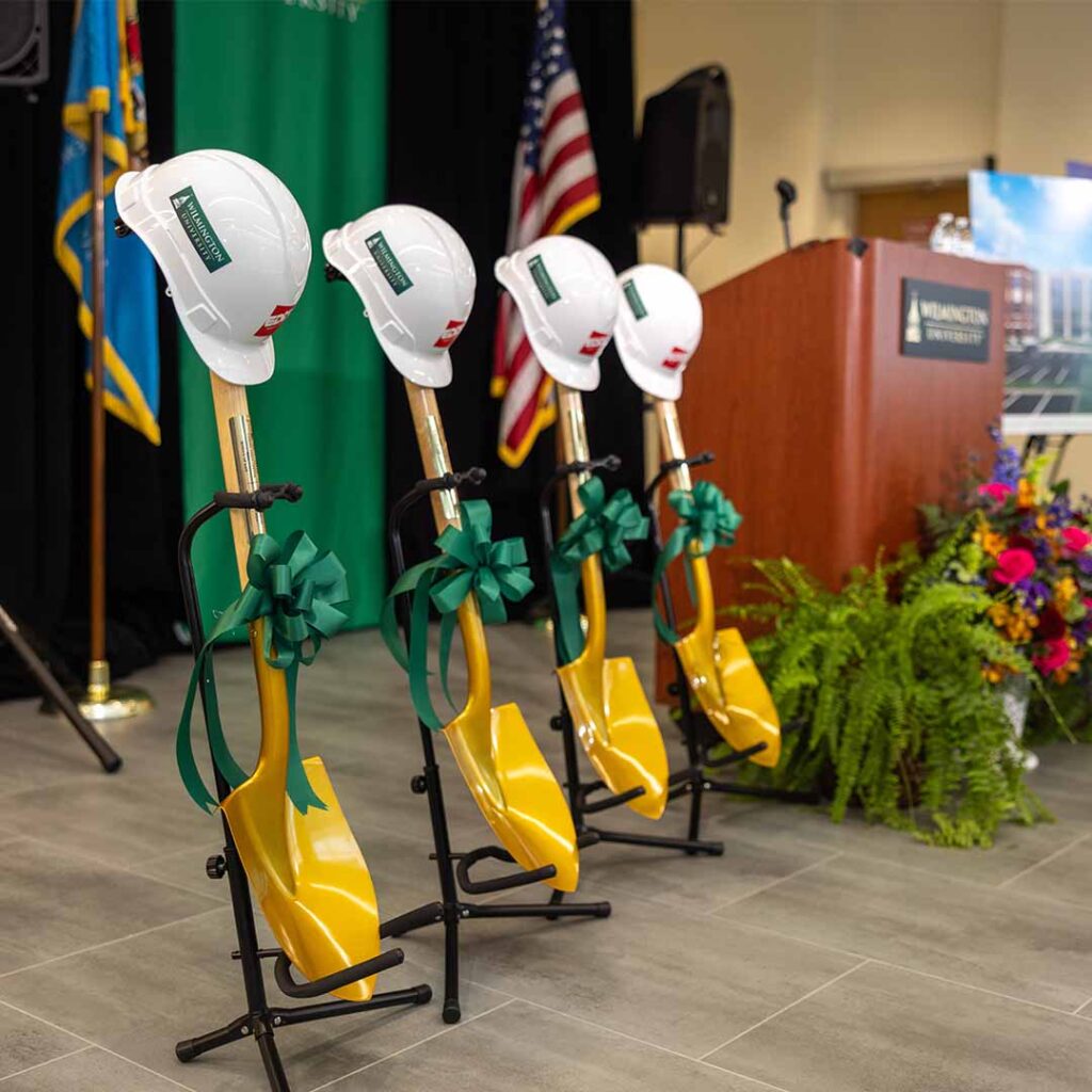 Shovels and construction hats next to Wilmington University podium.