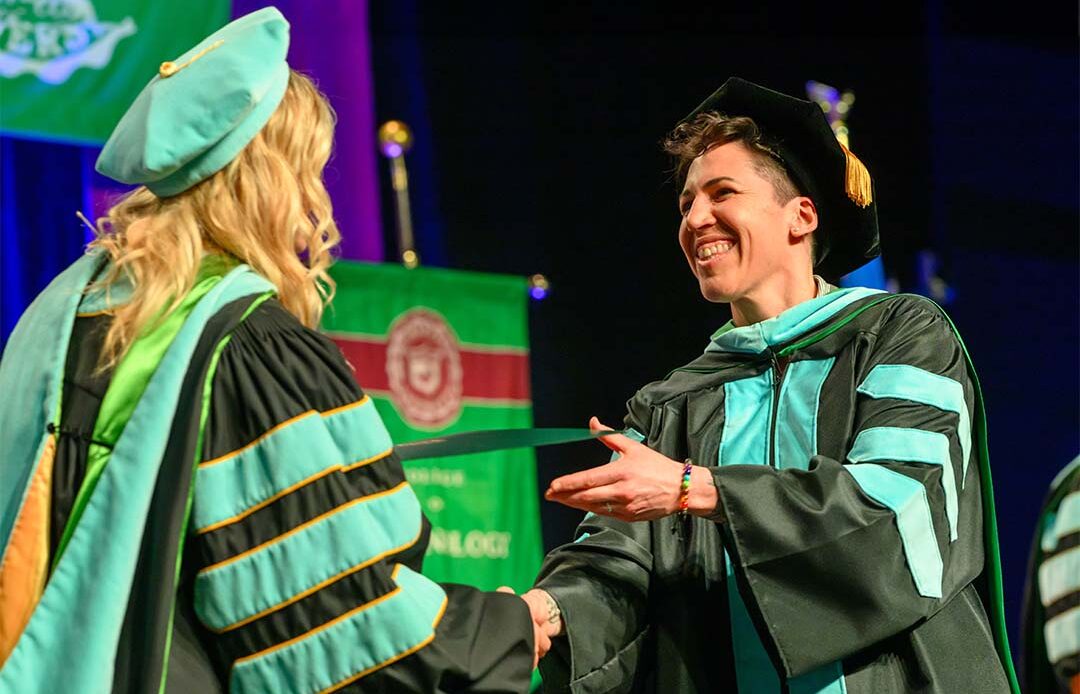 Doctoral student receiving their diploma on commencement day.