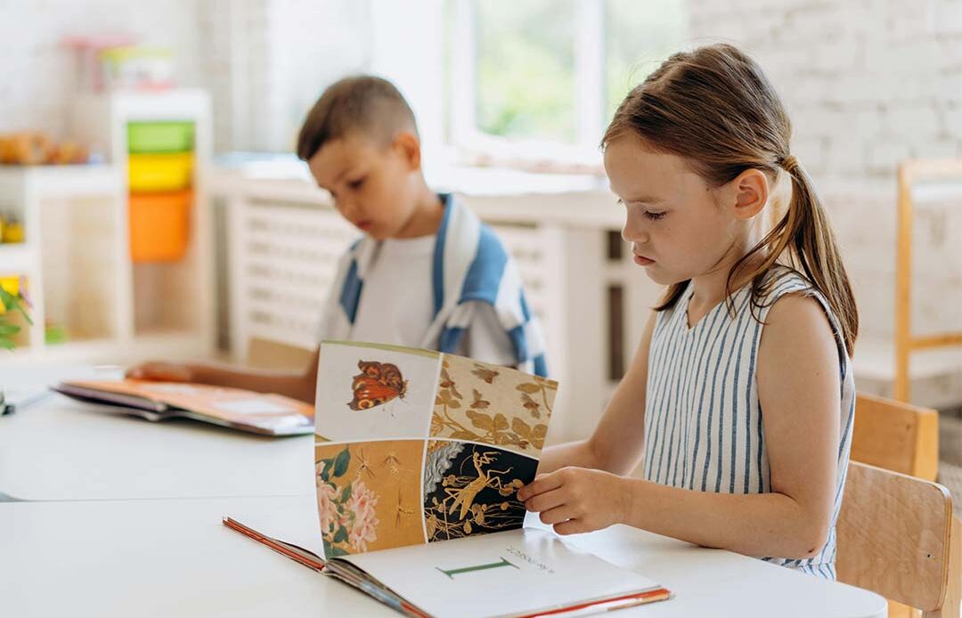 A young boy and girl learning to read at their desks.