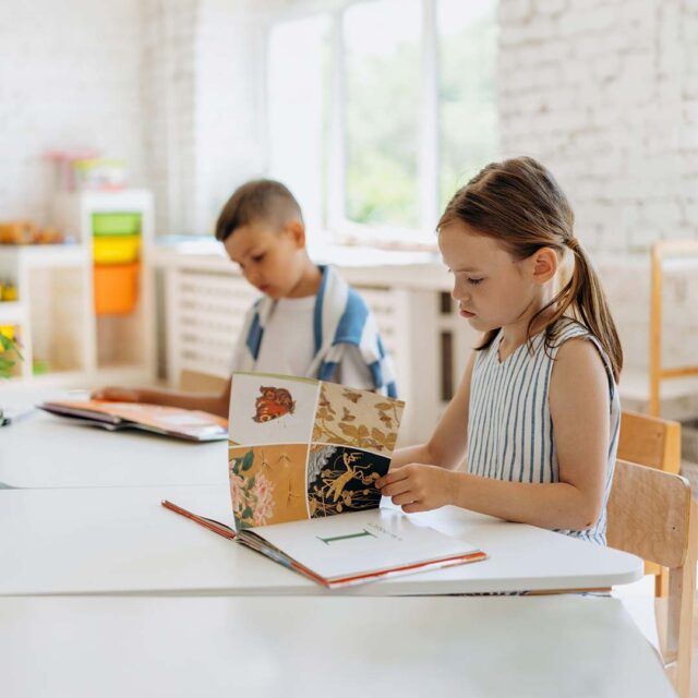 A young boy and girl learning to read at their desks.