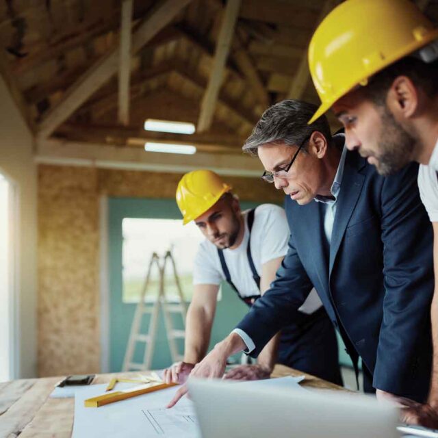 Construction workers planning project on site.