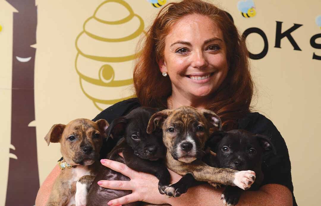 Alumni holding puppies in classroom.